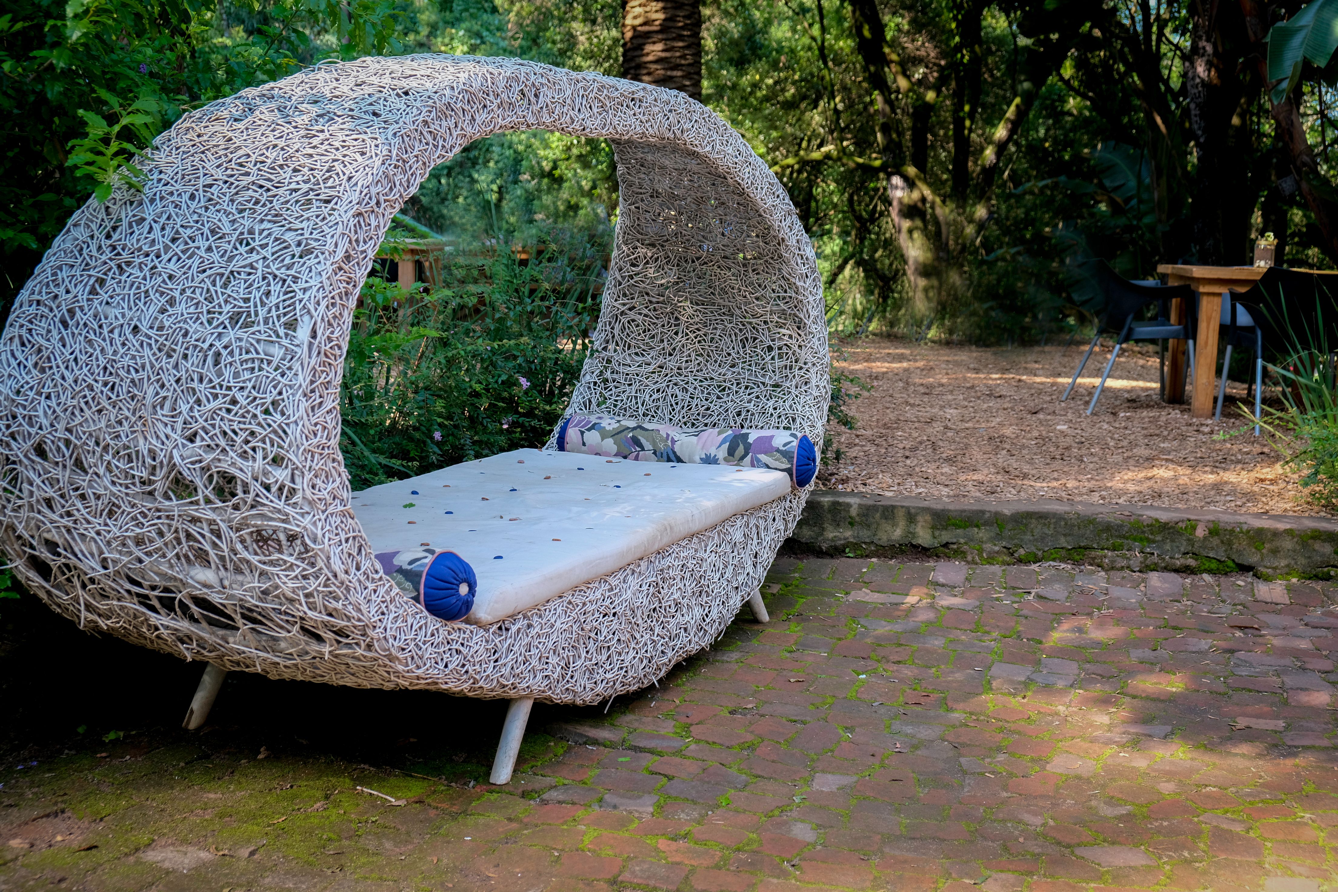 Elegant rattan daybed with comfortable cushions in a serene garden setting
