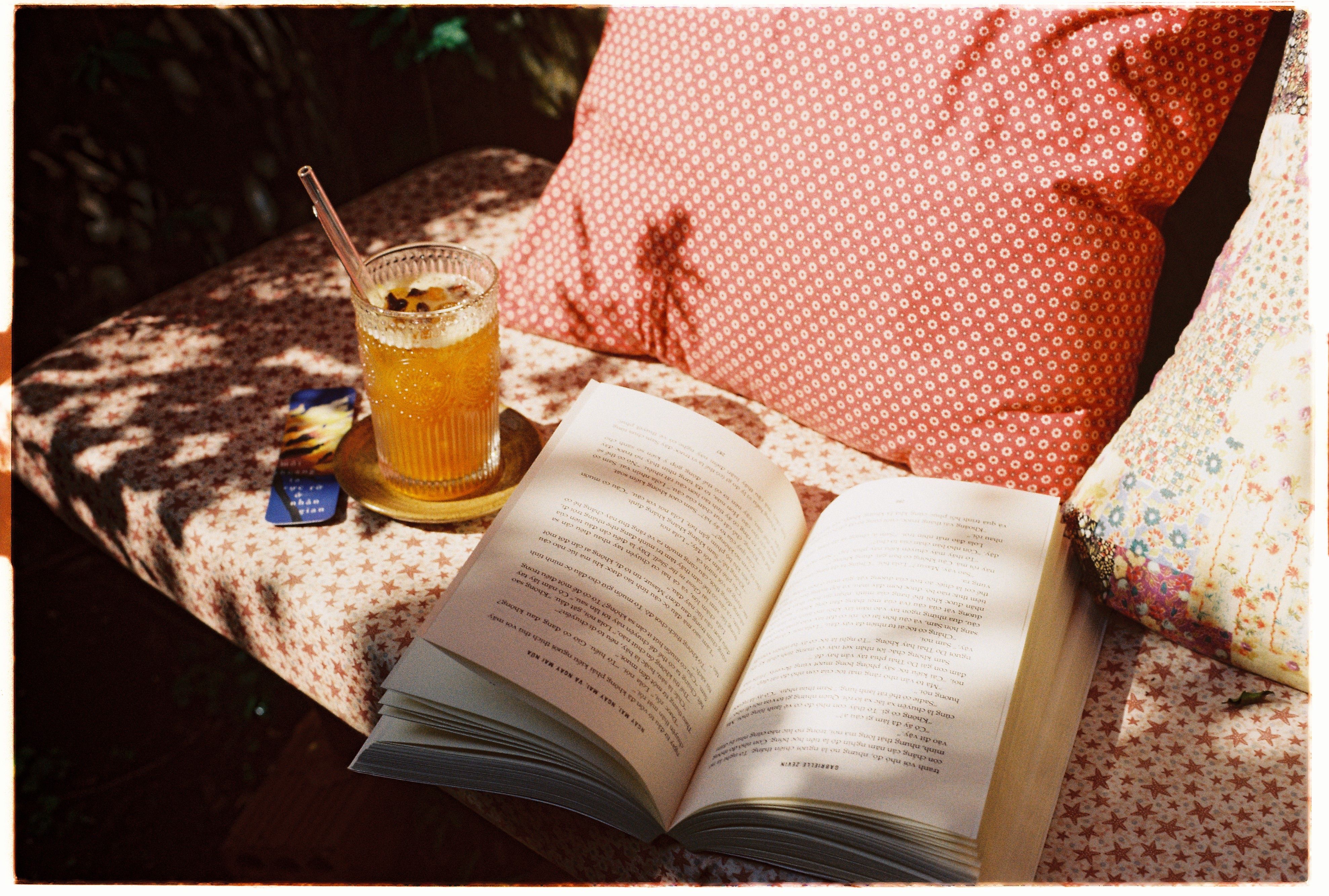 Sunny outdoor reading setup with a cool drink and comfy pillows